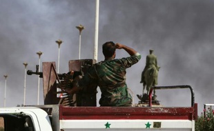 Un soldat syrien regarde la fumée d'une explosion à l'horizon, le 13 juillet 2015 à Hasakeh, au nord-est de la Syrie