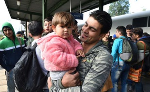 Un migrant, un enfant dans les bras, arrivé en train de Hongrie via Munich, sur le quai de la gare d'Eisenhuettenstadt, dans l'est de l'Allemagne, le 7 septembre 2015