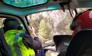 A bord d'un hélicoptère, le géologue de la métropole Nice Côte d'Azur inspecte les parois surplombant la route de la Vésubie