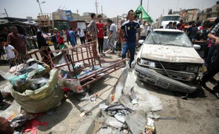 Des passants constatent les dégâts après l'explosion d'une voiture piégée près d'un marché du grand quartier chiite Sadr City, dans le nord de Bagdad le 11 mai 2016