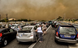 Les voitures sont bloquées à la route nationale fermée pendant un feu de forêt à Kineta, près d'Athènes, le 23 juillet 2018.