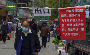 Un homme marche à côté d'un panneau annonçant les politiques de circulation dans les rues de Lanzhou, dans la province du Gansu (nord-ouest de la Chine), le lundi 25 octobre 2021.