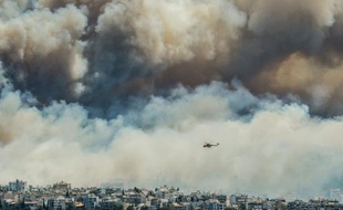 Un hélicoptère vole au-dessus des flammes à Athènes, en proie à un incendie, le 17 juillet 2015