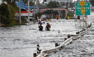 Des Thaïlandais marchent dans une rue inondée de Bangkok, le 25 octobre 2011.