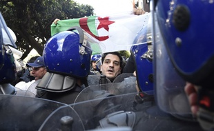 Un des nombreux manifestants ce dimanche 24 février à Alger entouré par un important dispositif policier.