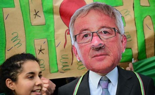 Un militant opposé au Partenariat transatlantique de commerce et d'investissement (TTIP) manifeste devant la Commission européenne à Bruxelle le 9 décembre 2014, un masque du président de la Commission européenne Jean-Claude Juncker sur le visage