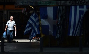 Un homme passe devant des drapeaux grecs déployés sur une échoppe du centre d'Athènes, le 13 juillet 2015
