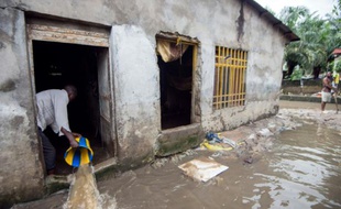 Un homme vide l'eau qui inonde sa maison à Limete, à Kinshasa, le 9 décembre 2015