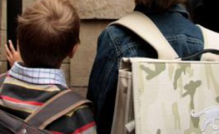 Des enfants patientent devant une école primaire.