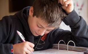 Un adolescent faisant ses devoirs à la maison.