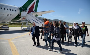 Les réfugiés syriens qui accompagnent le pape François dans l'avion qui le ramène de l'île grecque de Lesbos au Vatican, où ils seront hébergés, sur le tarmac de l'aéroport de Mytilène, le 16 avril 2016.