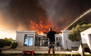 Un habitant tente de protéger sa maison des flammes à La Couronne, près de Marseille, mardi 4 août.