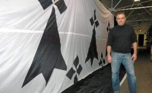 Jean Bourrassier devant le drapeau breton géant confectionné par sa société.