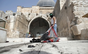 Un Palestinien masqué par un bandeau du Hamas sort un apis brûlé de la mosquée Al-Aqsa, à Jerusalem, après une intervention de la police israélienne, le 13 septembre 2015.