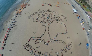 Des dirigeants d'ethinies indiennes amazoniennes du Pérou rassemblés pour réclamer des droits sur leurs territoires ancestraux dessinent avec leurs corps un arbre géant sur la plage de Lima, le 6 décembre 2014