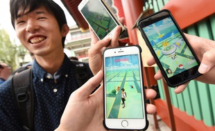 Des étudiants japonais montrent l'application Pokémon Go sur leur smartphone, à Tokyo, le 22 juillet 2016