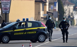 Des policiers italiens, avec des masques, contrôlent les entrées de la ville de Zorlesco, au sud est de Milan le 24 février 2020, pendant l'épidémie de coronavirus.