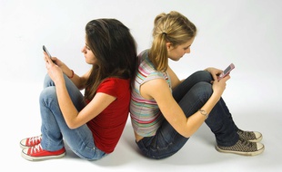: Adolescentes envoyant des SMS avec leurs téléphones portables