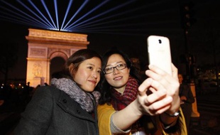 Des touristes chinoises prennent un selfie avec leur téléphone sur les Champs-Elysées le 31 décembre 2014