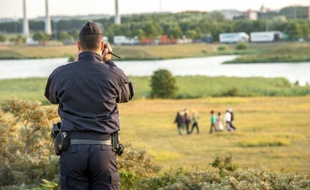 Un gendarme filme des migrants cherchant à s'intruire dans l'Eurotonnel pour passer en Angleterre, le 30 juillet 2015 à Coquelles, près de Calais