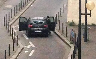 Des hommes armés devant l'immeuble de Charlie Hebdo à Paris le 7 janvier 2015
