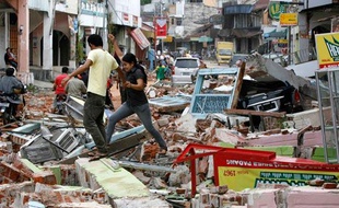 Un couple d'Indonésiens marche dans les décombres de la ville de Padang (Sumatra) le 1er octobre 2009 après le séisme du 30 septembre.