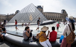 Des touristes devant le musée du Louvre, à Paris, en août 2018.