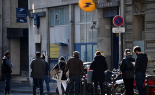Des clients attendent de pouvoir entrer dans leur bureau de poste, à Paris, resté ouvert pendant le confinement.
