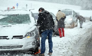 Des automobilistes obligés de mettre des chaînes sous la neige. Illustration.