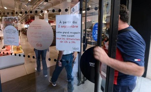 Des personnes entrent dans un magasin ouvert le dimache