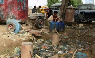 Un Pakistanais remplit d'eau des bidons dans un bidonville de Karachi, le 20 août 2015