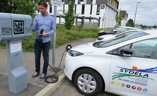 Un véhicule électrique du Sydela devant une borne de recharge.