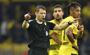 Un arbitre allemand sollicitant la VAR pendant le match Dortmund-Cologne