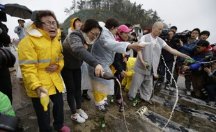 Un moine bouddhiste et des proches des passagers prient lors d'une cérémonie à Jindo, au sud de Séoul, le 18 avril 2014.