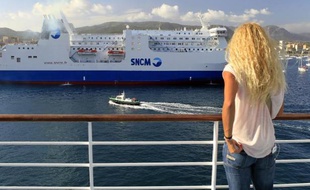 Une femme contemple le ferry de la SNCM "Paglia Orba" depuis un bateau de Corsica Ferries, le 10 juillet 2014 dans le port d'Ajaccio