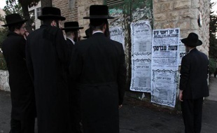 Des juifs ultra-orthodoxes lisent les affiches annonçant la mort du rabbin Moshe Tabersky, lors de l'attaque contre la synagogue à Jérusalem, le 18 novembre 2014