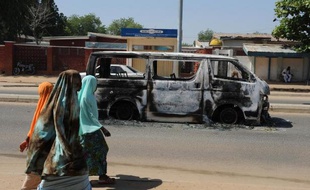 Des habitantes de Damaturu passent devant l'épave d'un véhicule incendié dans une rue de la ville, le 4 novembre 2011 dans le nord-est du Nigeria