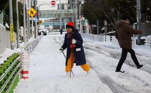 Une femme marche avec un baton dans les rues de Tokyo dimanche 9 février 2014, après une chute de 27 centimètres de neige.