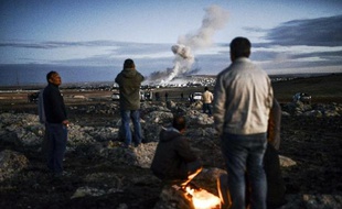 Des Kurdes observent de la fumée le 20 octobre 2014 dans la ville syrienne de Kobané depuis le village turc de Mursitpinar