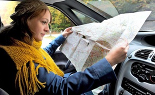 Conductrice égarée, cherchant son chemin a l'aide d'une carte routière.