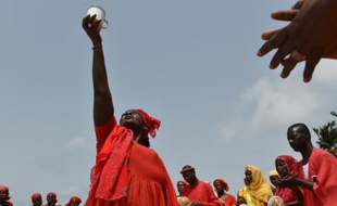 Une femme, membre d'une Eglise locale, brandit un bol d'eau, lors d'une prière sur la plage de Grand-Bassam en Côte d'Ivoire, le 1er avril 2016