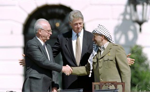Poignée de mains historique entre le Premier ministre israélien Yitzahk Rabin (d) et le chef de l'OLP Yasser Arafat, sous les yeux du président américain Bill Clinton (c), à la Maison Blanche le 13 septembre 1993