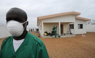 Un homme portant un masque de protection devant un centre de quarantaine pour les personnes atteintes du virus Ebola à l'aéroport d'Abidjan, le 12 août 2014