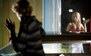 Une jeune femme fait un signe d'aurevoir à un homme.