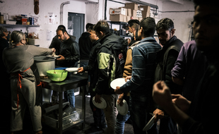 Des migrants afghans, iraniens et africains prennent un repas au "Refuge solidaire" de Briançon, dans le sud-est de la France, le 29 septembre 2020. Dépassé pas le nombre de réfugiés, le lieu a fermé depuis.