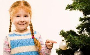 Une petite fille à côté d'un arbre de Noël