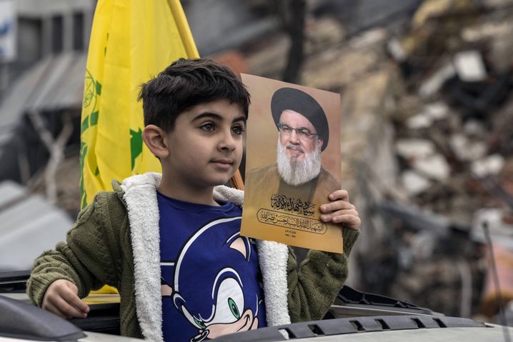 Un garçon déplacé portant une photo du leader assassiné du Hezbollah, Hassan Nasrallah, revient avec sa famille à Dahiyeh, à Beyrouth, au Liban, à la suite d'un cessez-le-feu entre Israël et le Hezbollah entré en vigueur, le mercredi 27 novembre 2024.