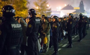 Des policiers slovènes encadrent les migrants sur le point de monter dans un bus le 28 octobre 2015 à Sentilj