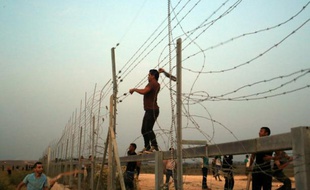 Des Palestiniens s'attaquent aux barbelés à la frontière entre Gaza et Israël, lors d'affrontements avec les forces de l'ordre israéliennes le 12 octobre 2015