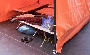 Un demandeur d'asile allongé sur un lit de camp dans un gymnase municipal à Nantes.